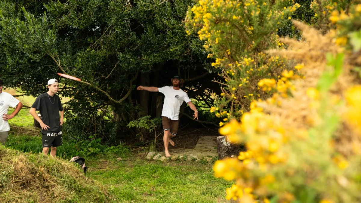 A forehand throw through the gorse-lined gully, disc mid-flight