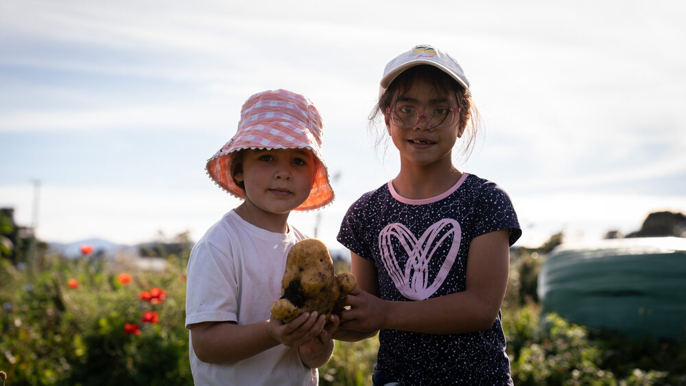 Two kids showing off their just-dug potatoes